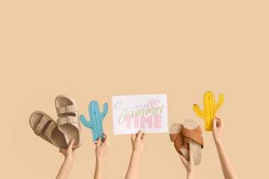 Elinde kağıt kaktüslü iki çift parmak arası terlik ve bej arka planda Mutlu Yaz Zamanı.