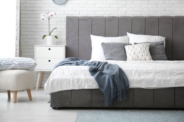 Şık bir yatak, ayna ve komodin aydınlık yatak odasında.