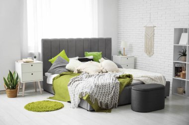 Yataklı, komodinli, puf ve raf üniteli modern yatak odası.