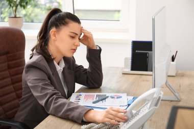 İş yerinde baş ağrısı çeken genç bir kadın.