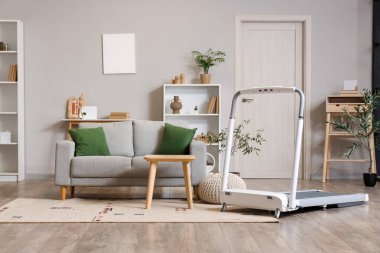 Koşu bandı ve kanepesi olan bir oturma odası.