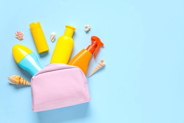 Farklı güneş kremi şişeleri ve mavi arka planda deniz kabukları olan kozmetik çanta.