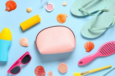Kozmetik çanta, güneş kremi ve mavi arka planda aksesuarları olan güzel bir kompozisyon