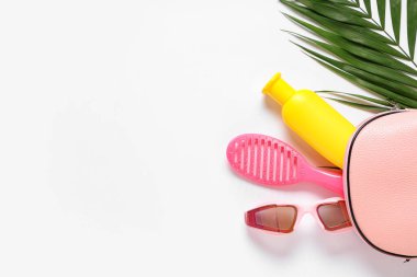 Beyaz arkaplanda kozmetik çanta, tarak, güneş gözlüğü ve güneş kremi ile güzel bir kompozisyon