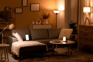 Parlak lamba, rahat kanepe, sehpa ve dizüstü bilgisayar şık oturma odasında.