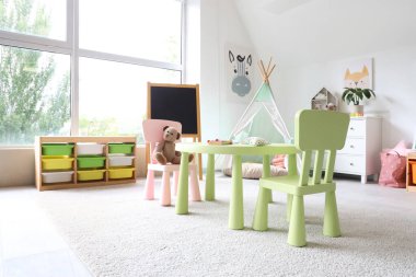 Anaokulunda içinde oyuncaklar, çadır ve karatahta olan hafif oyun odasının içi.