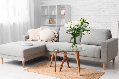 Gri kanepe ve sehpanın üzerinde nilüfer çiçekleri olan şık bir oturma odası.