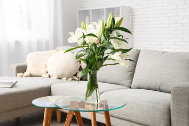 Gri kanepe ve sehpanın üzerinde nilüfer çiçekleri olan şık bir oturma odası. Yakın plan.