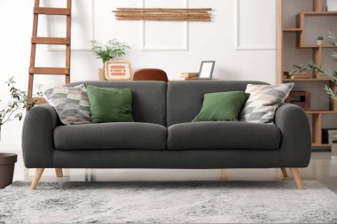 Sıcak kanepe, merdiven, raf ünitesi ve oturma odasında dekoratif zeytin ağacı.