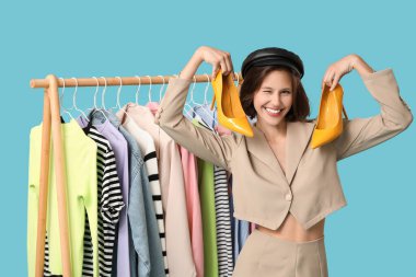 Mavi arka planda farklı giysileri olan güzel genç bir kadın.