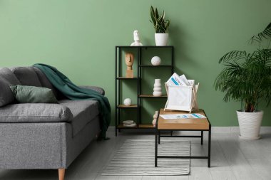 Oturma odasındaki siyah kanepenin yanındaki sepetin üzerinde dergiler vardı.