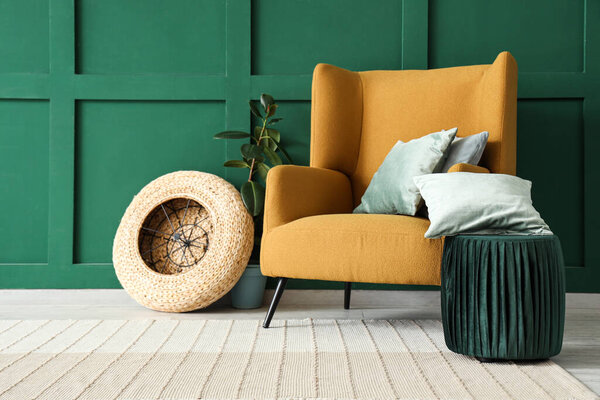 Interior of living room with brown armchair, houseplant, cushions and pouf