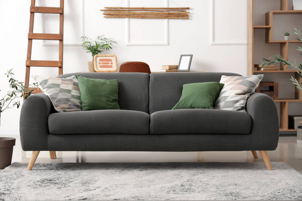 Cozy sofa, ladder, shelving unit and decorative olive tree in living room
