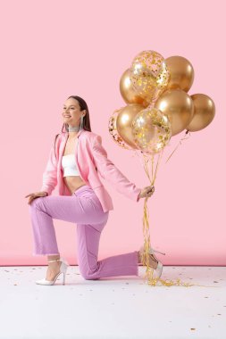 Pembe arka planda hava balonları olan güzel genç bir kadın.