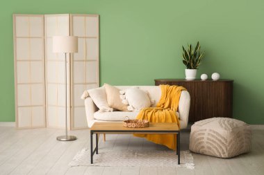 Yastıklı kanepe, puf, sehpa ve oturma odasında katlanan ekran.