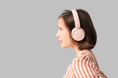 Gri arka planda modern kulaklıklı güzel bir kadın.