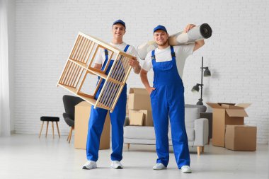 Yükleyiciler taşınma gününde evde raf ünitesi ve halı taşıyorlar.