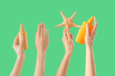 Yeşil arka planda güneş kremi şişeleri ve deniz yıldızı olan kadın eller.