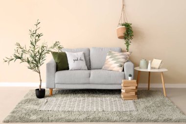 Güzel oturma odasının içinde rahat bir kanepe, sehpa, yastıklar ve zeytin ağacı var.