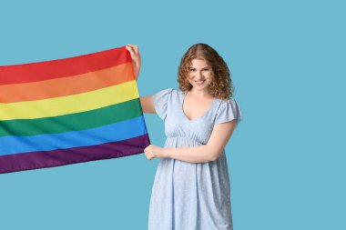 Beautiful young woman with LGBT flag on blue background