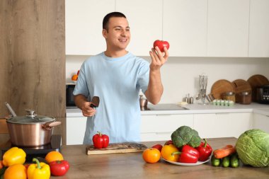 Mutfakta domates pişiren genç adam.