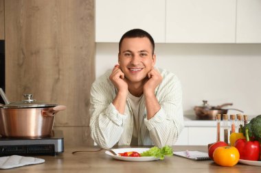 Mutfaktaki masada pişmiş yemeği olan genç bir adam.