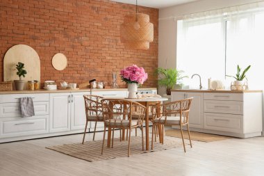 Mutfaktaki yemek masasında şakayık çiçekli vazo.