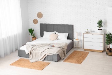 Büyük yataklı, çekmeceli ve bitkilerle dolu modern bir oda.