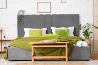 Rahat yatağı, raf ünitesi, bank ve bitkileri olan modern bir oda.