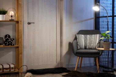 Oturma odasının içinde raf ünitesi, sandalye, kapı ve parlayan lambalar.