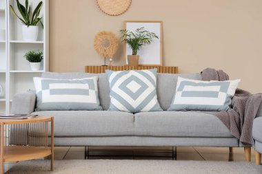 Rahat kanepesi, sehpası, raf ünitesi ve saksısı olan bir oturma odası.