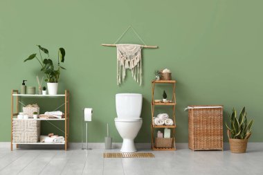 Tuvalet, raflar ve çamaşır sepeti tuvaletteki yeşil duvarın yanında.