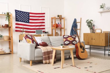 Gri kanepe, rugby topu, gitar ve Amerikan bayrağıyla oturma odasının içinde.
