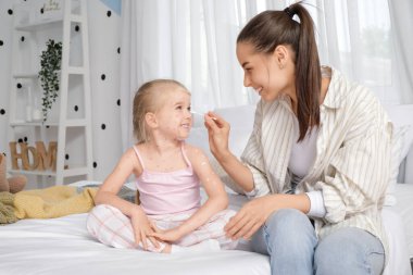 Anne yatak odasında kızına suçiçeği bulaştırıyor.