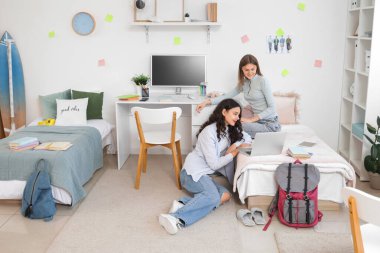 Yurt odasında dizüstü bilgisayarla çalışan kız öğrenciler.