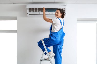 Kadın teknisyen evde klima tamir ediyor.