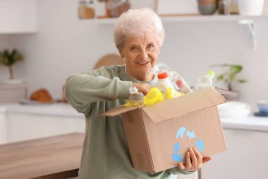 Mutfakta çöp kutusu olan yaşlı bir kadın. Atık sıralama kavramı