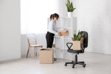 İş kadını taşınma gününde ofisteki raflardan karton kutuları alıyor.