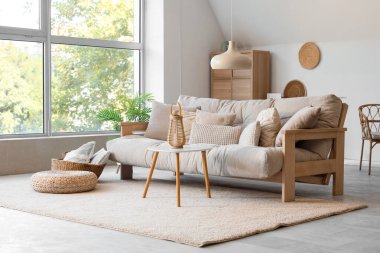 Oturma odasında rahat bir kanepe, sehpa ve asılı bir lamba var.