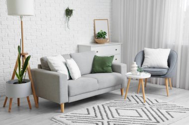 Gri kanepesi, koltuğu ve masası olan oturma odasının içinde.