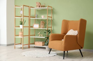 Oturma odasının iç tarafındaki yeşil duvarın yanındaki raf ve rahat koltuk.