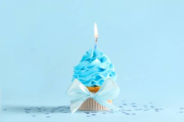 Tatlı doğum günü keki, yanan mum ve mavi arka planda konfeti.