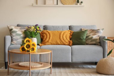 Oturma odasındaki sehpada rahat bir kanepe ve yabani çiçekler.