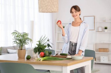 Yemek odasında domatesli genç bir kadın.