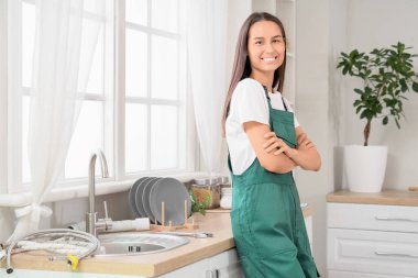 Kadın tesisatçı mutfakta lavabonun yanında.