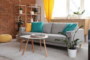 Konforlu kanepe, koltuk, sehpa ve oturma odasının içindeki sarı perdeler.