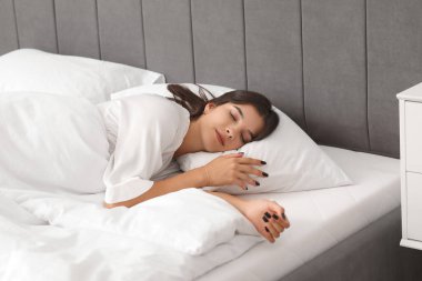 Genç bir kadın yatağında uyuyor.