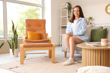 Evdeki yumuşak kanepede oturan genç kadın.