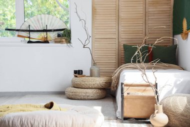 Yatak odasının içinde katlanmış perde, vazolarda ağaç dalları ve Çin dekorasyonu var.