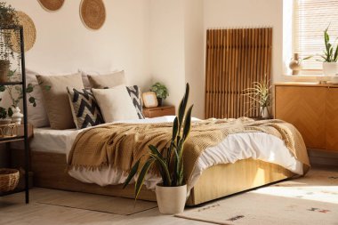 İçinde bitkiler, katlanan ekran ve tuvalet olan rahat bir yatak odası.